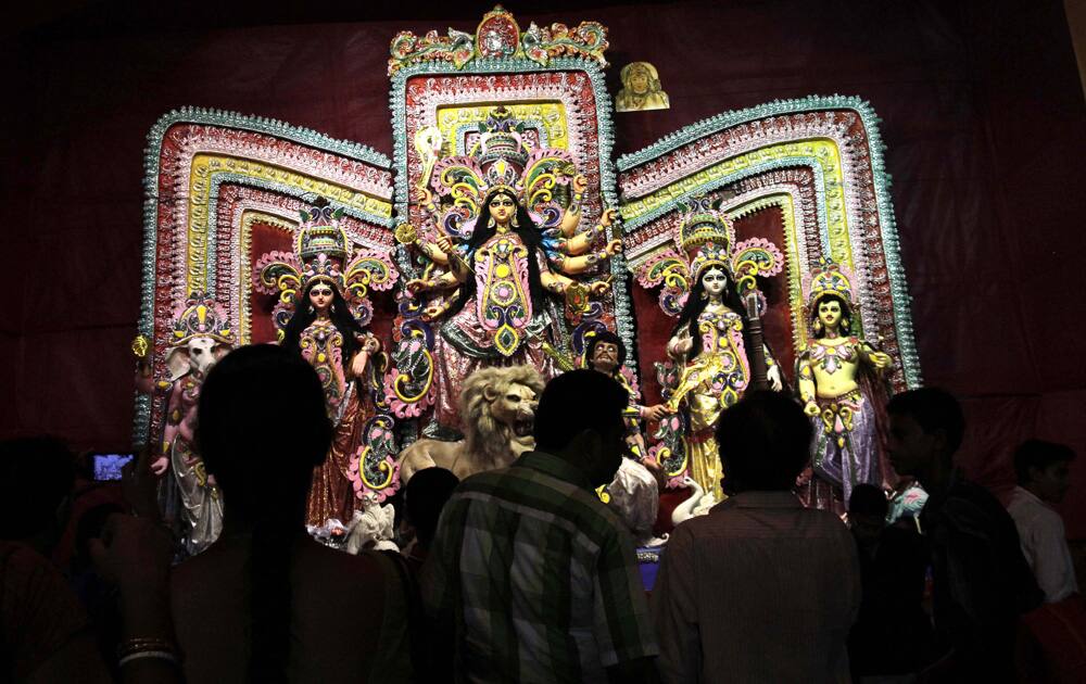 Devotees watch idol of decorated Hindu goddess Durga during Durga Puja festival, in Kolkata.