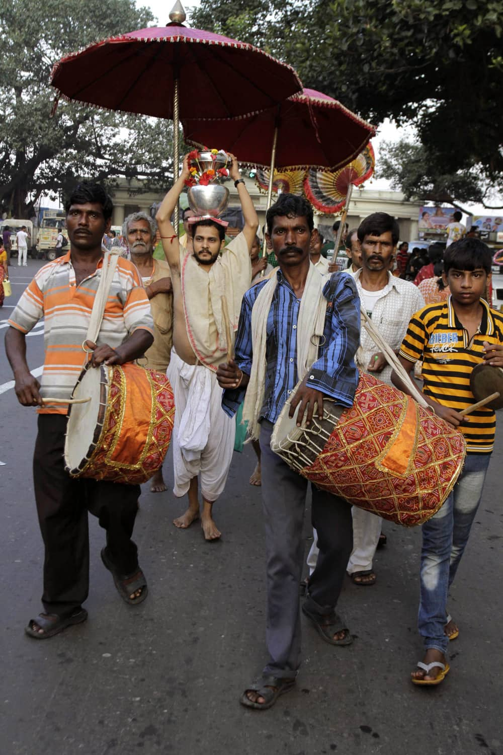 A devotee carries holy water from the Ganges River as he marches through a street in a procession of Hindu festival Durga Puja in Kolkata.