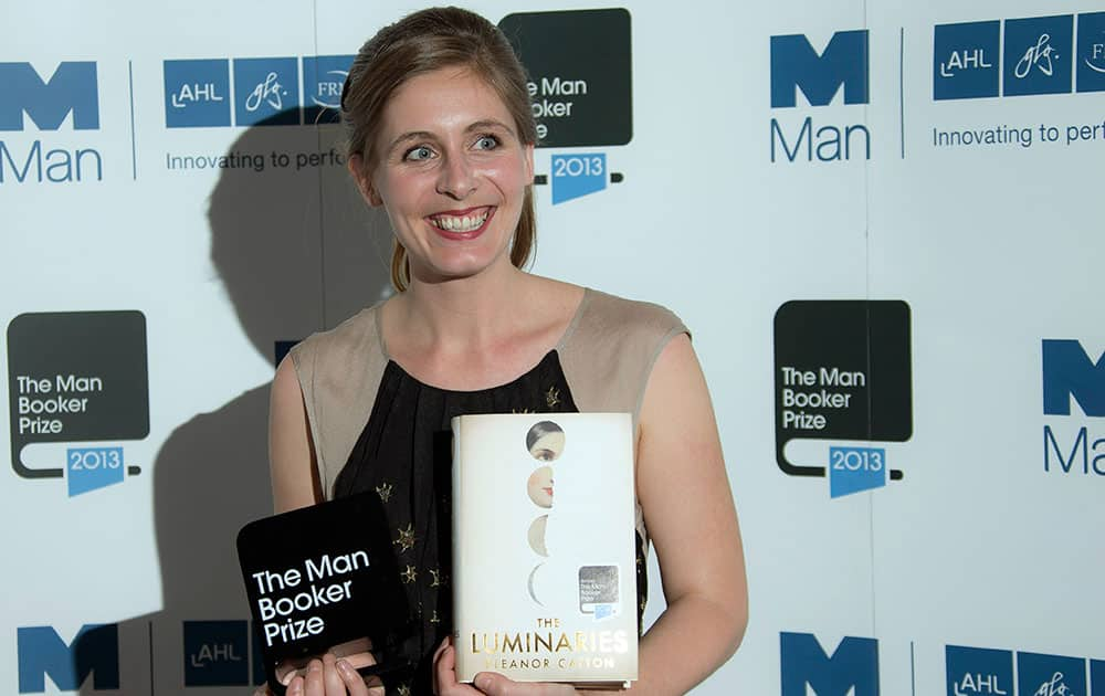 New Zealand author Eleanor Catton poses after being announced the winner of the Man Booker Prize for Fiction, holding her prize and her book for the photographers, in central London.