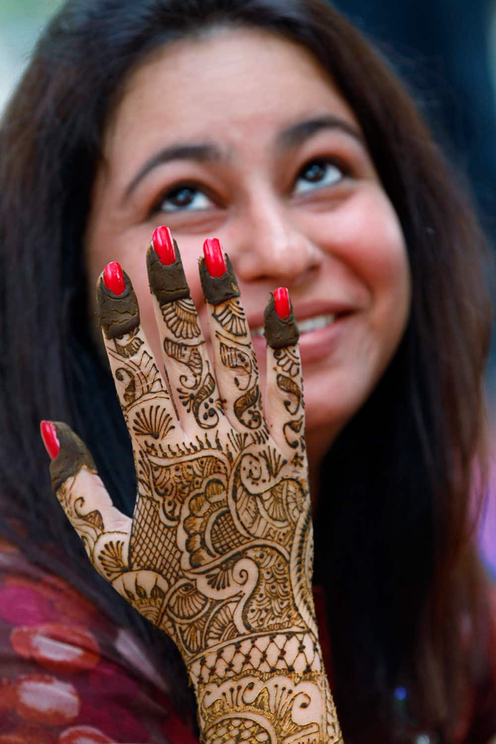 A woman dries her hand after getting it painted with henna on the eve of Hindu festival 'Karwa Chauth' in Allahabad.