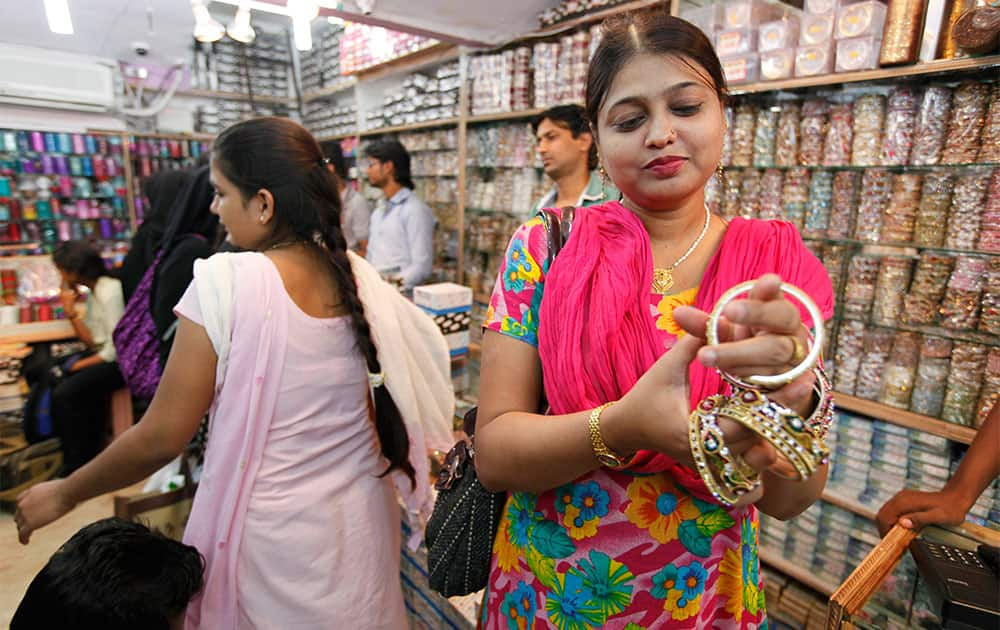 A woman tries bangles as she shops for them on the eve of of Hindu festival 