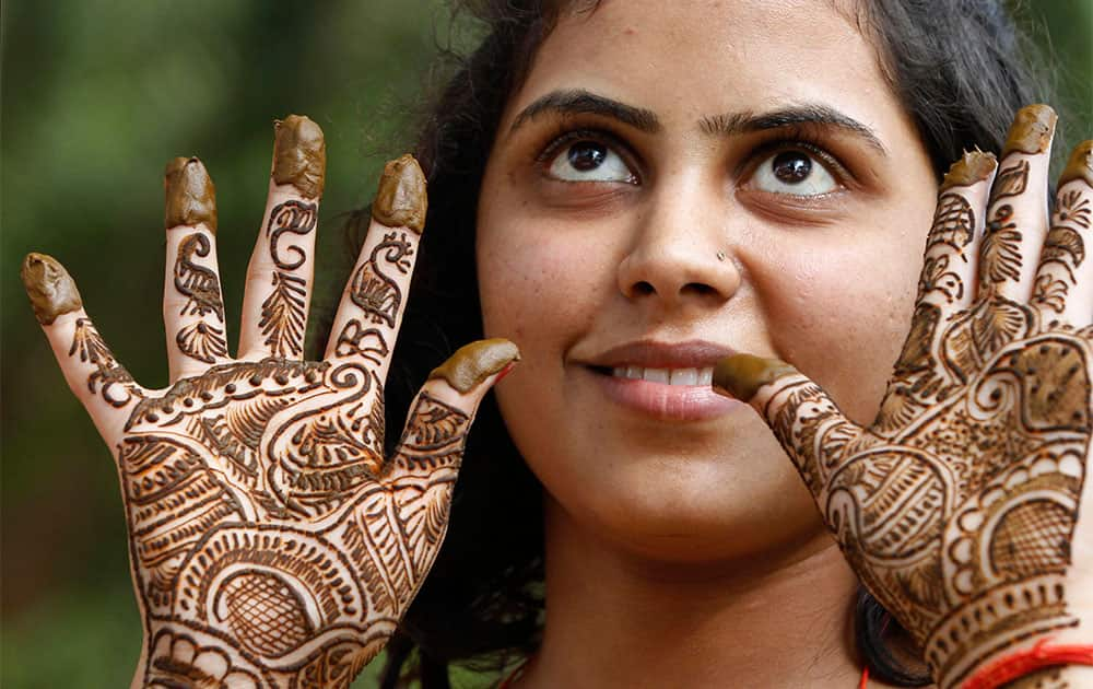 A woman shows her husband her hand after getting it painted with henna on the eve of of Hindu festival 