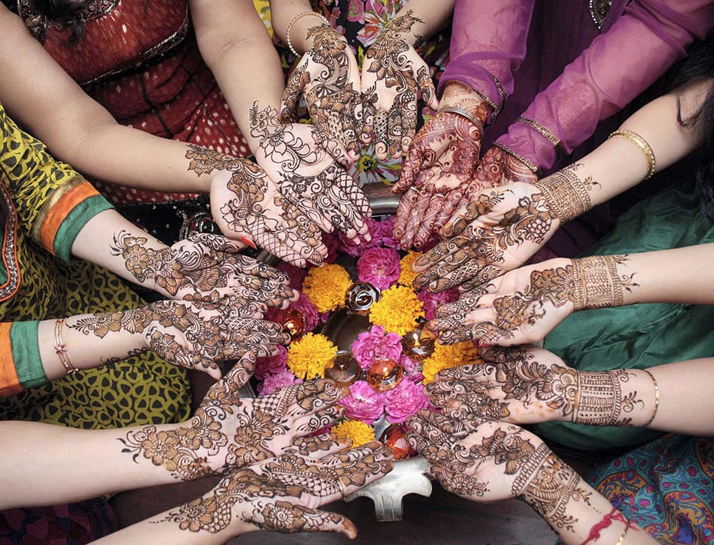 Women showing their hands after applying heena on the eve of 'Karva Chauth' in Amritsar.