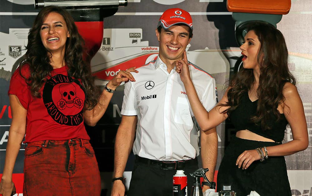 McLaren Formula One driver Sergio Perez of Mexico is flanked by Bollywood actresses Neha Dhupia and Aditi Rao Hydari during a promotional event in New Delhi.