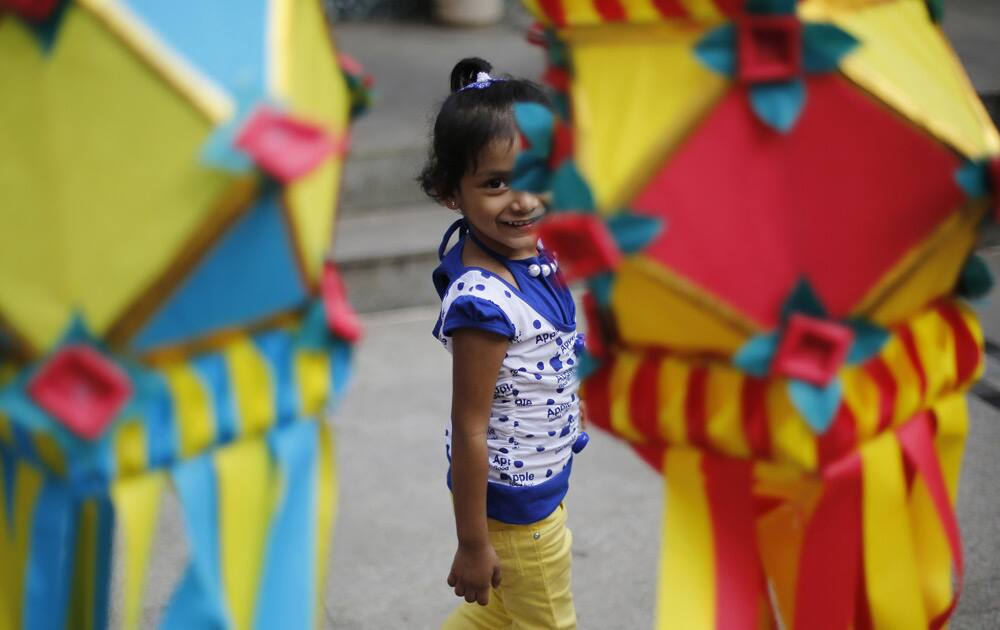 A girl smiles as shewalks past lanterns hung at a roadside stall ahead of Diwali in Mumbai.