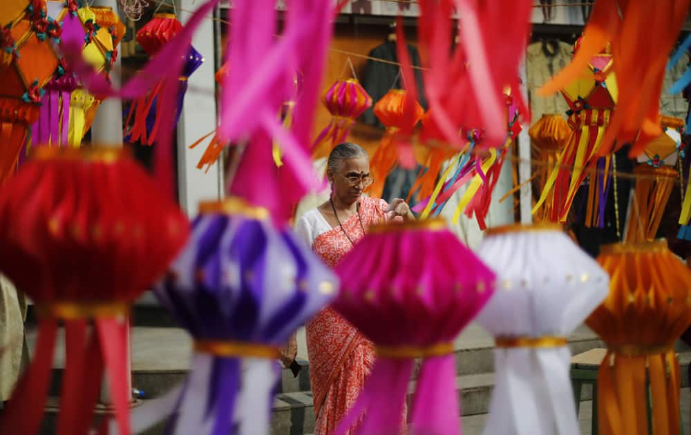 A woman points a lantern on display at a roadside stall ahead of Diwali in Mumbai.