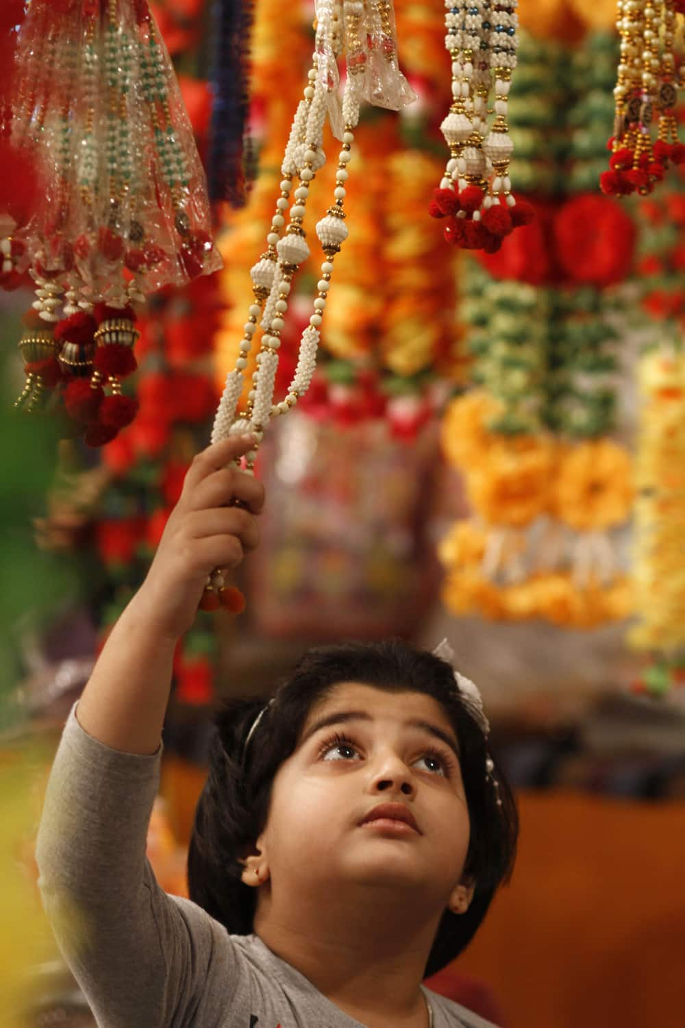 A girl touches an artificial garland on display at a shop ahead of Diwali in Allahabad.