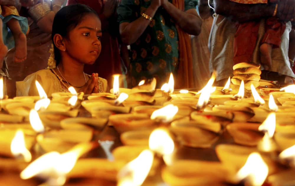 A Hindu devotee offers a prayer in front of oil lamps during Diwali, or the Hindu festival of lights at Batu Caves Hindu temple in Kuala Lumpur, Malaysia.