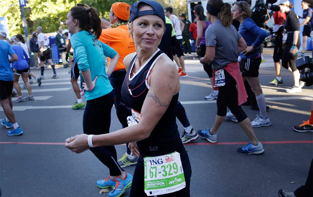 Actress Pamela Anderson smiles after crossing the finish line at the 2013 New York City Marathon in New York.