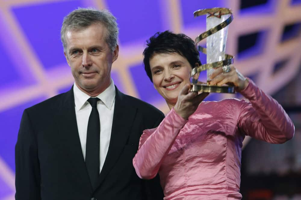 French actress Juliette Binoche poses after receiving a trophy in tribute to her lifetime career from French director Bruno Dumont, left, at the Marrakech International Film Festival.