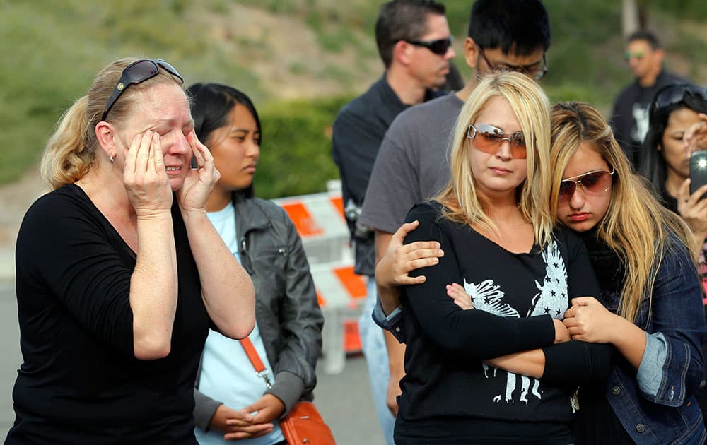 Amie Kaz, left, and Marjan Bauman and her daughter Alexandra Bauman, right, join others at the site of the auto crash that took the life of actor Paul Walker and another man, in the small community of Valencia, Calif.