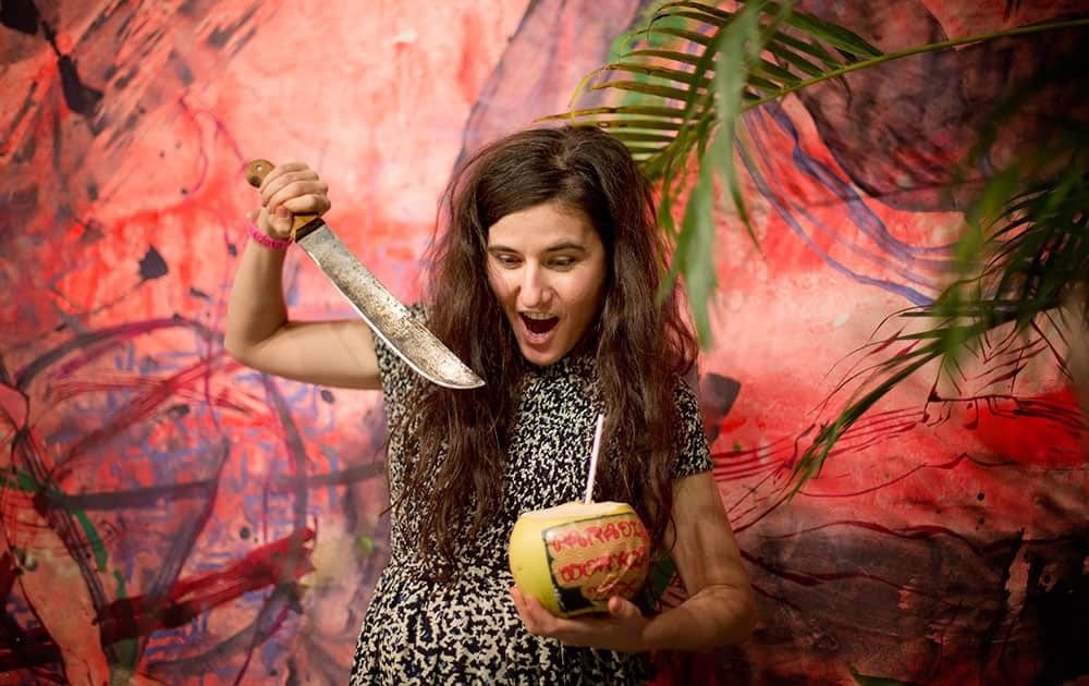 Naomi Fisher `jokes around` after opening a coconut as part of her installation, `Paradise Walking` at Art Basel In Miami Beach show,  in Miami Beach, Fla.