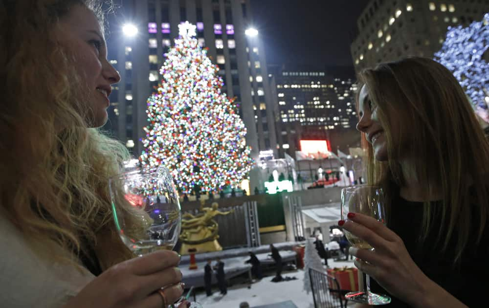 Anna Ladner and Vanja Ojes Dahlberg sip Champagne in front of the Rockefeller Center Christmas tree after it was lit, in New York. 