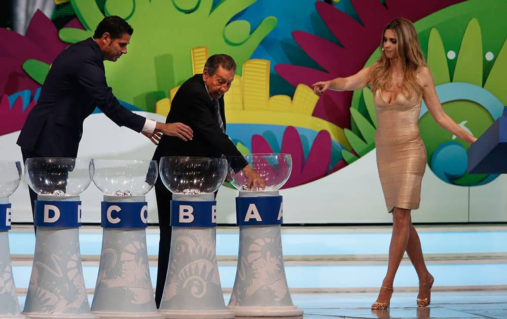 Former soccer great and World Cup winner Alcides Ghiggia of Uruguay is supported by former World Cup player Fernando Hierro of Spain, left, and Brazilian actress Fernanda Lima, right, during the draw ceremony for the 2014 soccer World Cup in Costa do Sauipe near Salvador, Brazil.