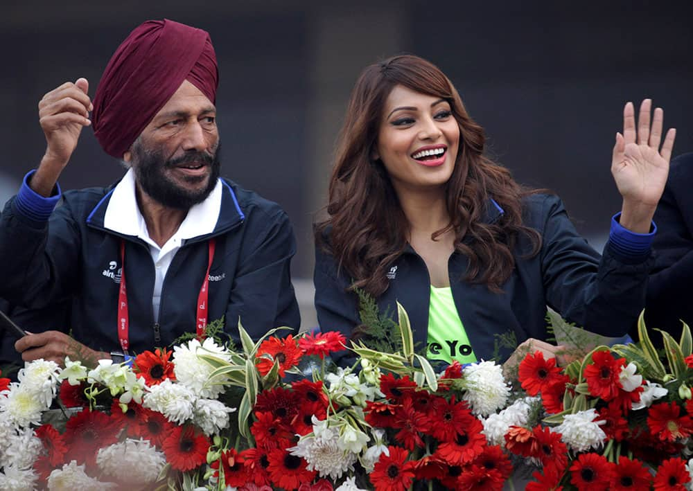 Former Indian athlete Milkha Singh and Bollywood actor Bipasha Basu wave to the participants during the Delhi Half Marathon in New Delhi.