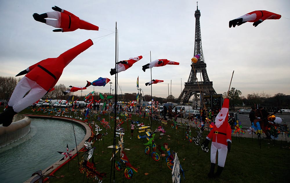 Kites in the shape of Santa Claus glide in the wind as part of a kite exhibition next to the Eiffel Tower in Paris.