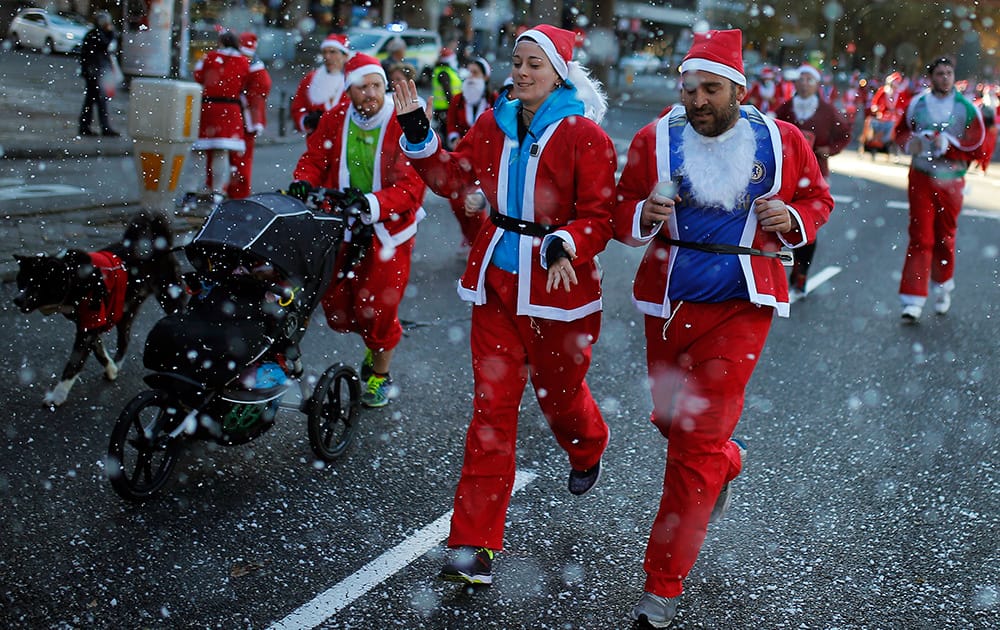 Revelers dressed as Santa Claus run under fake snow, during a marathon in Madrid, Spain.