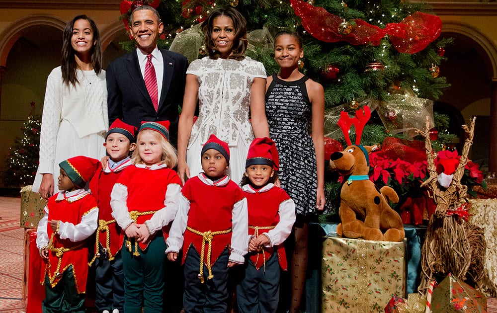 The first family, from left, Malia Obama, President Barack Obama, first lady Michelle Obama, and Sasha Obama, pose with children dressed like elves at the National Building Museum in Washington.