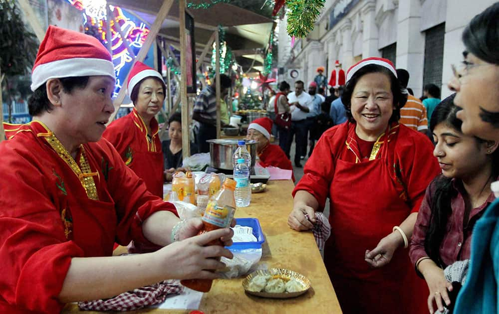 Chinese women wearing Santa hats sell food on a road side stall ahead of Christmas in Kolkata.