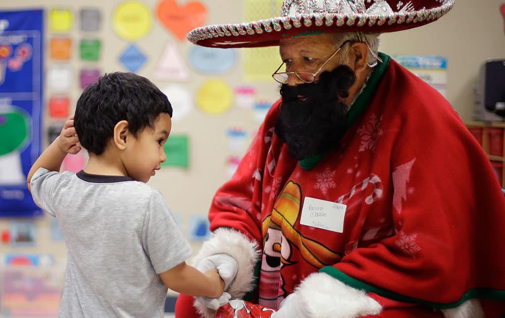 Pancho Claus, Rudy Martinez, right, visits with students at Knowlton Elementary School, in San Antonio.