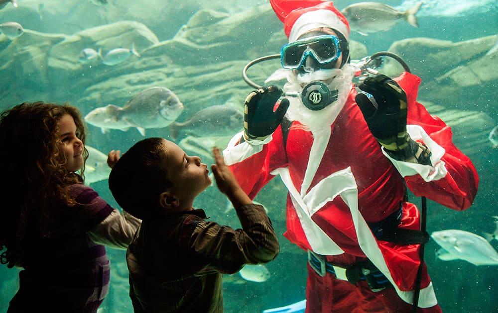 A child greets a diver dressed as Santa Claus and waving at children at the Creta Aquarium in the city of Iraklio, on the Greek island of Crete.