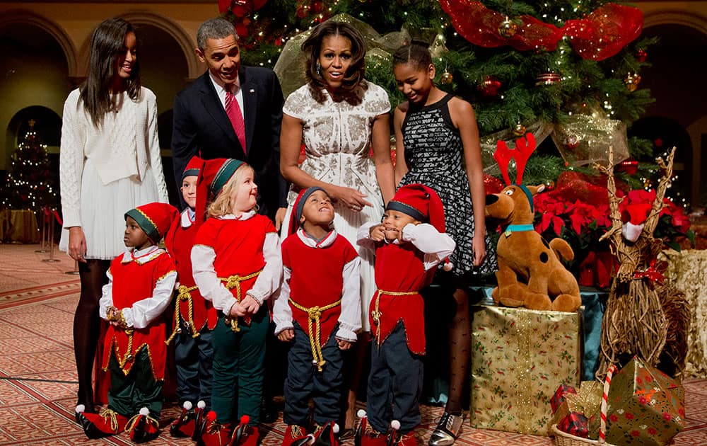 The first family, from left, Malia Obama, President Barack Obama, first lady Michelle Obama, and Sasha Obama, join children dressed like elves at the National Building Museum in Washington.