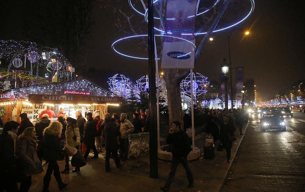 People stroll along the Champs Elysees avenue at the Christmas market, in Paris.