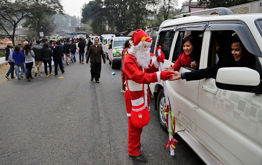 An Indian man dressed as Santa Claus distributes sweets among people in a car ahead of Christmas in Umsning, in Meghalaya.