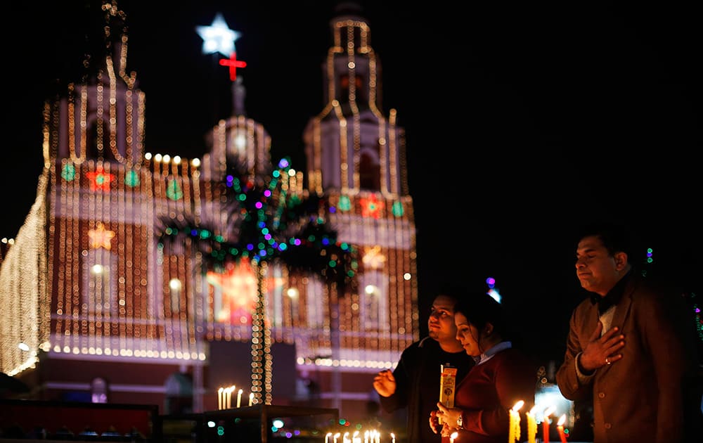 Christian people light candles and pray at the illuminated Sacred Heart’s Cathedral on Christmas Eve in New Delhi.