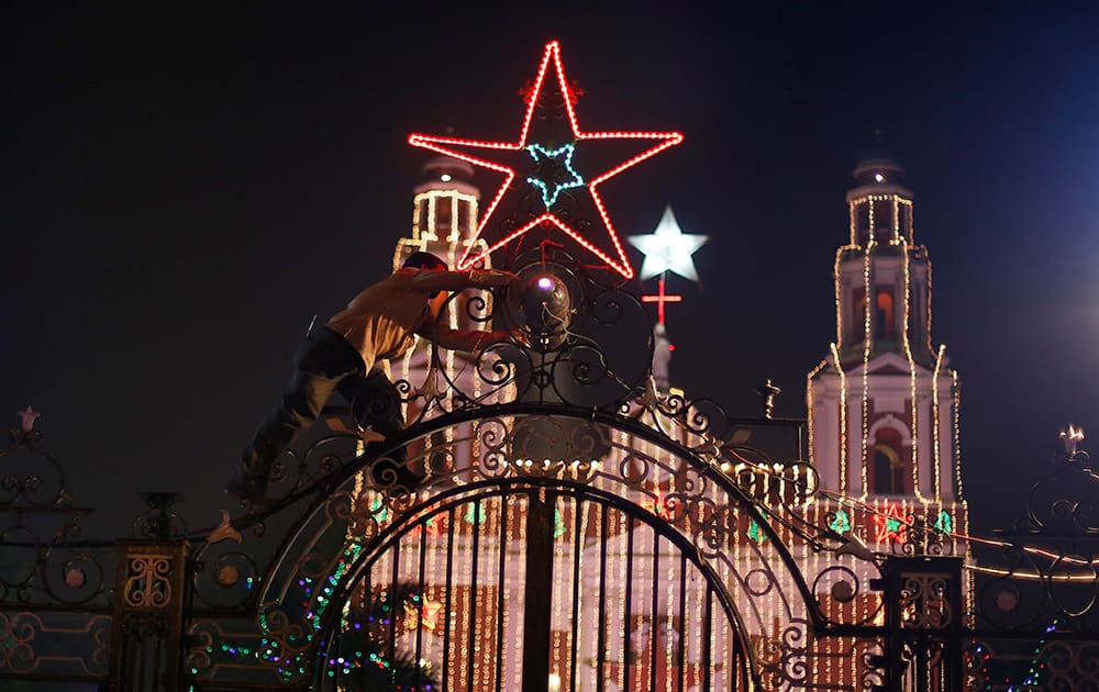 A worker installs decorative lights on the gate of the Sacred Heart’s Cathedral on the eve of Christmas in New Delhi.