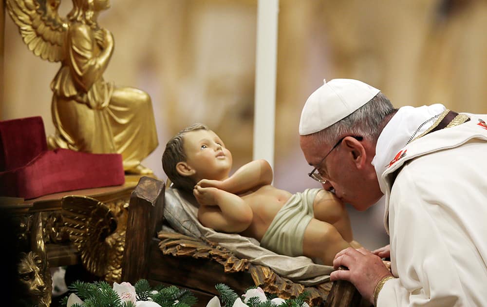 Pope Francis kisses a statue of baby Jesus as he celebrates the Christmas Eve Mass in St. Peter's Basilica at the Vatican.