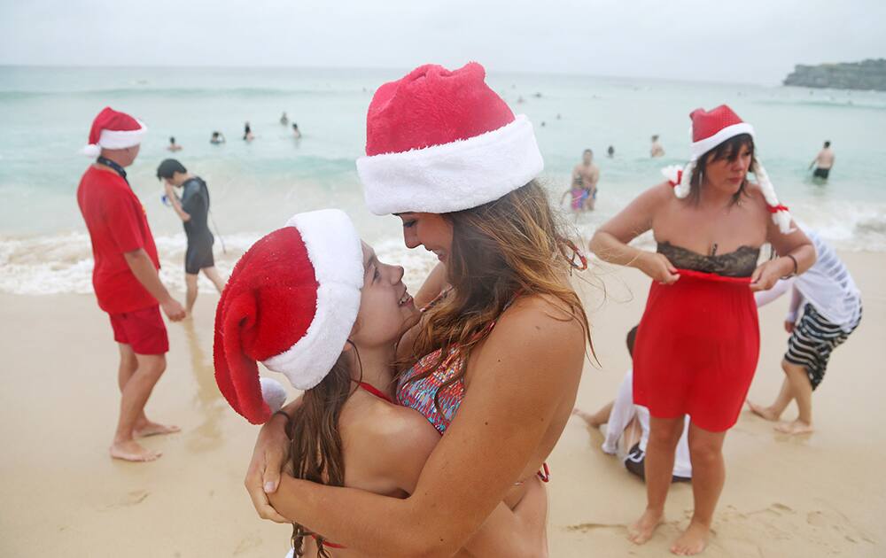 Lucy O'Grady, center right, hugs her little sister Poppie O'Grady, to keep her warm as the visitors from Birmingham in the United Kingdom celebrate Christmas Day at Bondi Beach in Sydney.