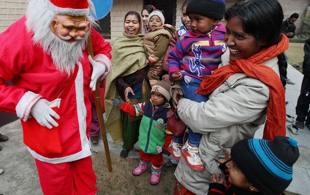 A man dressed as Santa Claus distributing candies among the children in the lawns of Holy Family Catholic church on the occasion of Christmas in Srinagar.