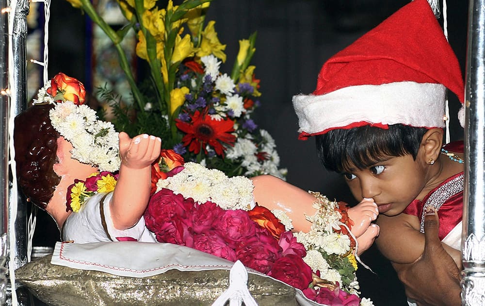 A child kisses the feet of an infant Jesus Christ after attending prayer on the occasion of Christmas in Santhome Church in Chennai.