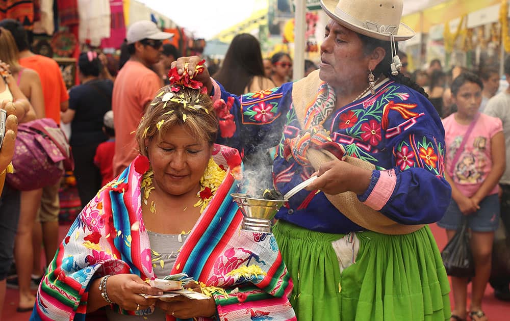 A shaman, right, performs a new year's ritual to bring good luck to her client for the coming year, at the Market of Wishes in Lima, Peru.