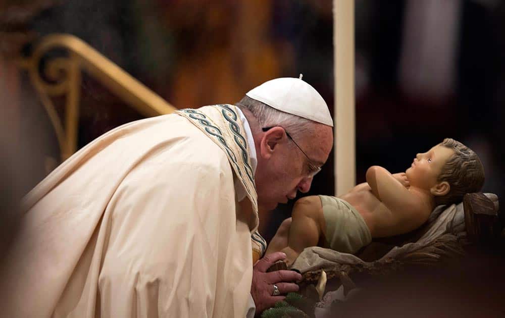 Pope Francis kisses a baby Jesus statue as he arrives to celebrate a New Year's Eve vespers service in St. Peter's Basilica at the Vatican.