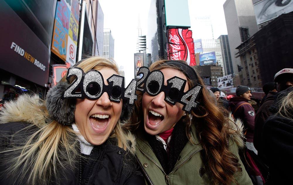 Veronica Boshen and Brittany Wells, of Allentown, Pa., pose for a photo with their 2014 glasses while waiting for the celebration to begin in Times Square on New Year's Eve, in New York.