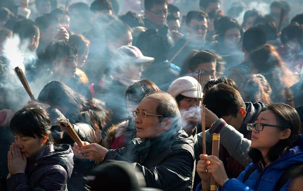 Chinese worshippers burn incense while offering prayers on the first day of the New Year at the Yonghegong Lama Temple in Beijing.