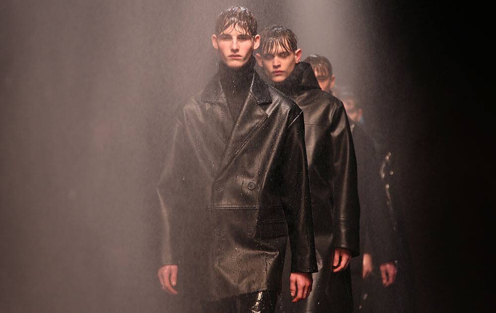 Models walk through water spray as they wear designs created by Topman Design during London Collections for Men Autumn/Winter 2014, at the Old Sorting Office in central London.