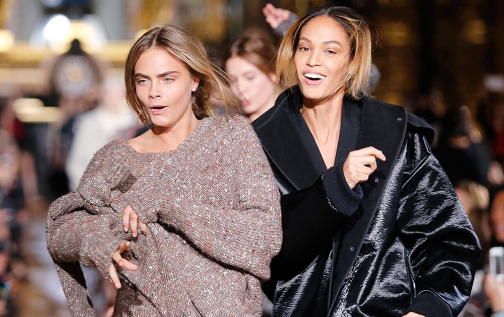 Models Cara Delevingne, left, and Joan Smalls dance during Stella McCartney's ready-to-wear fall/winter 2014-2015 fashion collection presented in Paris.