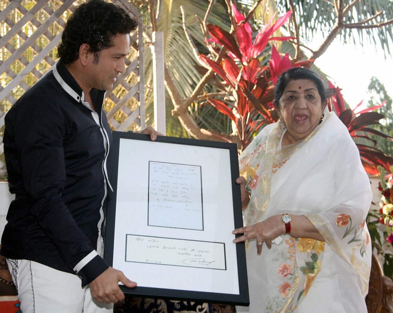 Veteran singer Lata Mangeshkar offers a copy of her songs to Sachin Tendulkar during an event in Mumbai.