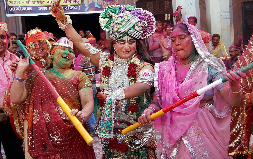 A Hindu devotee dressed up as Lord Krishna along with other devotees during a Holi celebration in Aligarh.