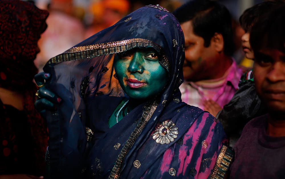 A Hindu woman, drenched in colored water, looks on at the Nandagram Temple famous for Lord Krishna during Lathmar Holi festival in Nandgaon.