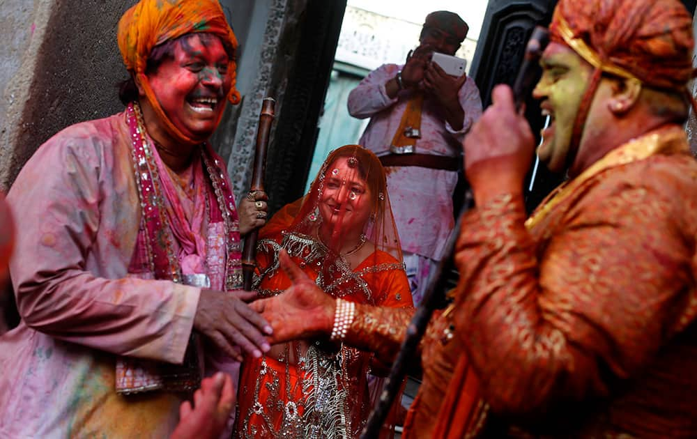 A man from Nandgaon village greets a villager from Barsana as a woman from village Nandgaon waits with a wooden stick during the Lathmar Holy festival in the legendary hometown of Lord Krishna in Nandgaon.