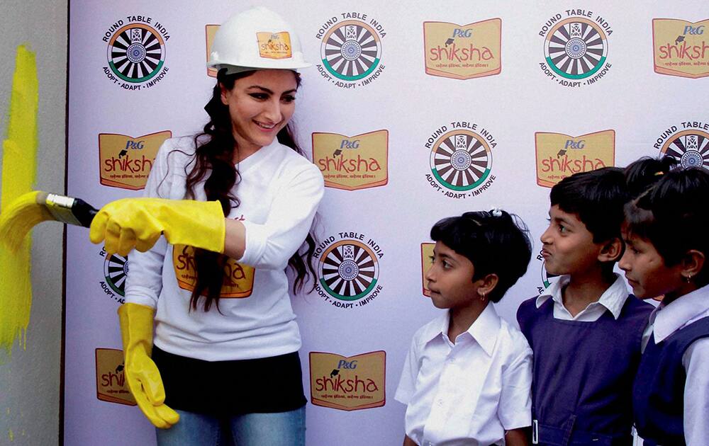 Bollywood actress Soha Ali Khan paints a wall with the school children in Hyderabad.