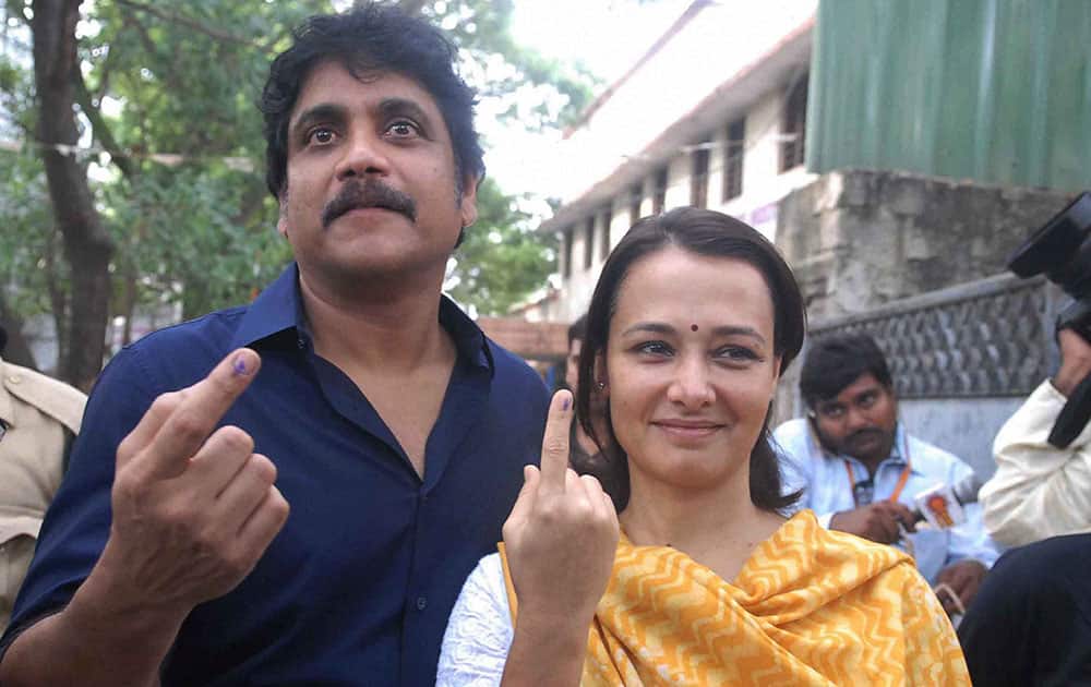 Actor Nagarjuna with his wife Amala show their ink finger after casting their votes at a polling station in Hyderabad.