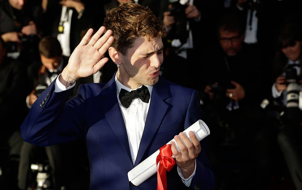 Director Xavier Dolan shields his eyes from the sun as he poses after winning the Jury Prize award for the film Mommy, which was shared with Jean-Luc Godard's Goodbye to Language (Adieu au langage)during a photo call following the awards ceremony at the 67th international film festival, Cannes.