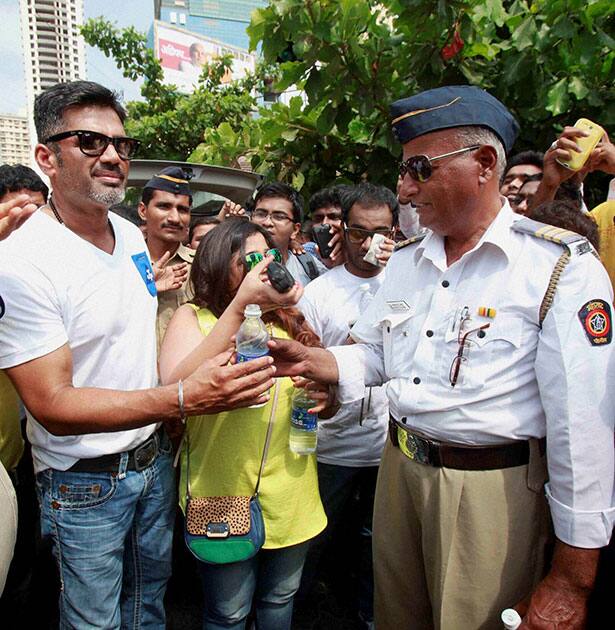 Bollywood actor Sunil Shetty offers a water bottle to a traffic police man during a campaign at Worli in Mumbai.