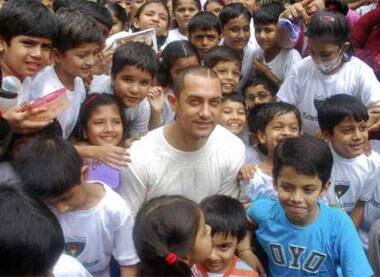 Bollywood actor Aamir Khan (C) and child actor Darsheel Safary (R, in blue) pose with school children after unveiling the DVD of their film 