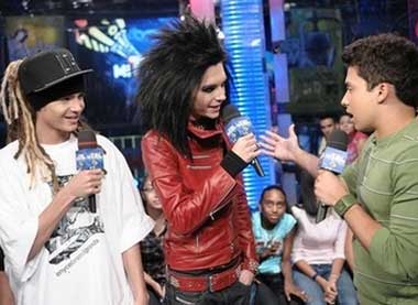 Tokio Hotel band members Tom Kaulitz, left, and Bill Kaulitz talk with host Carlos Santos, right, during an appearance on MTV's MiTRL.